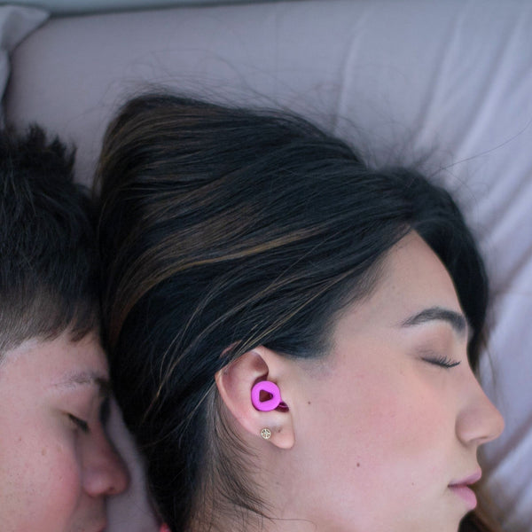 Pareja durmiendo mientras usa los tapones para los oídos reutilizables Mood Earplugs Focus Pink, diseñados para reducir el ruido de los ronquidos