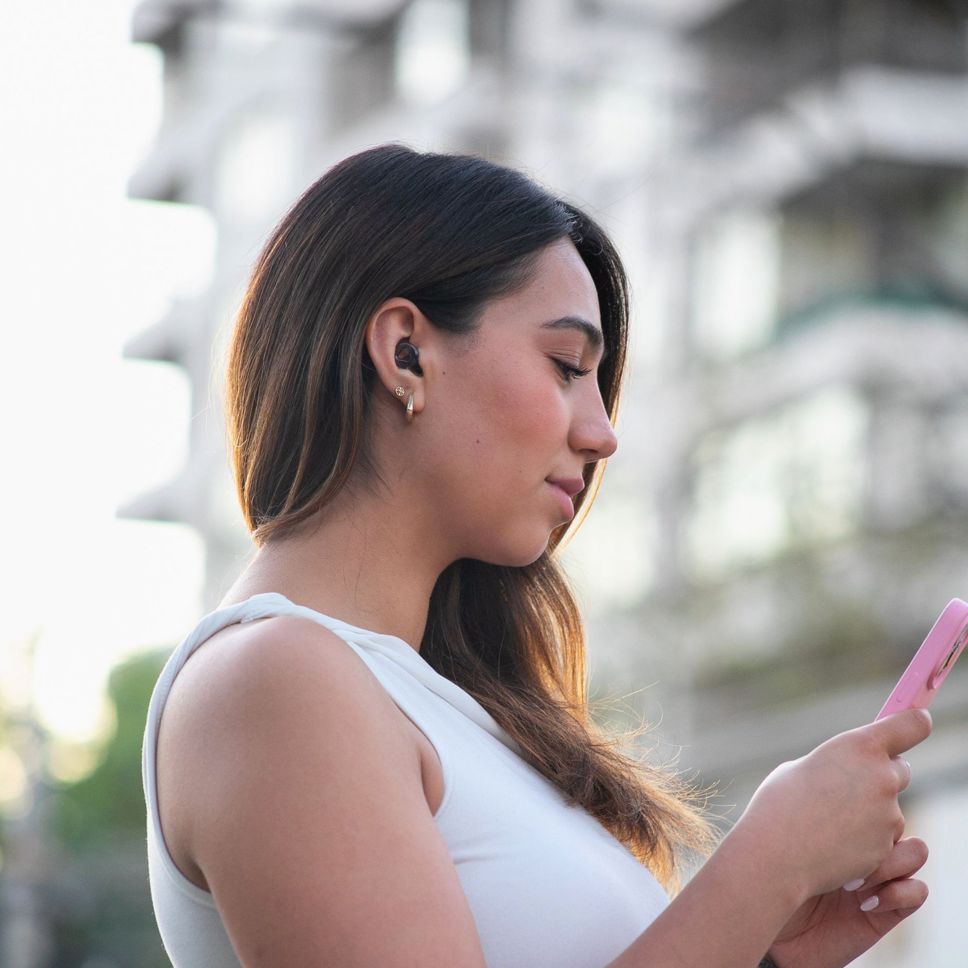 Mujer con los tapones Mood Earplugs Pro Onyx mientras camina por la ciudad, perfectos para reducir el ruido sin perder conexión con el entorno.