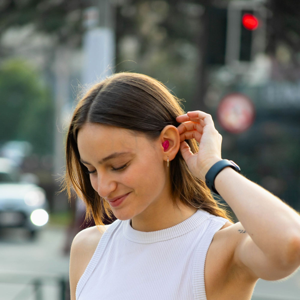 Mujer colocando los tapones para los oídos Mood Earplugs Pro rosa, adecuados para personas neurodivergentes o sensibles al ruido