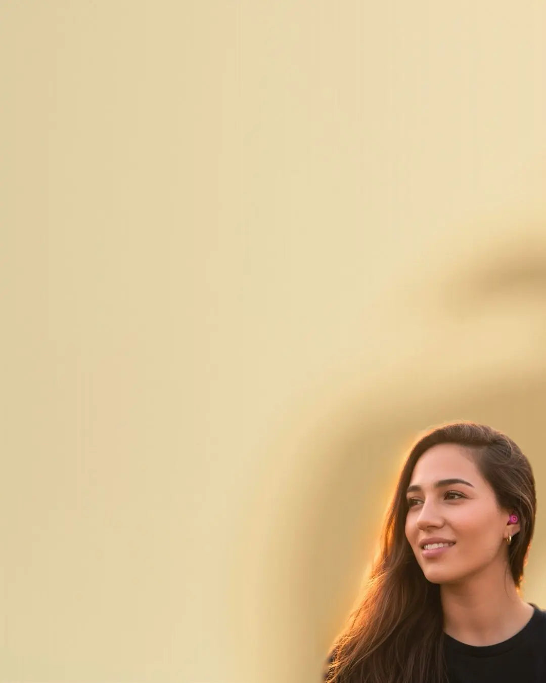Mujer joven sonriendo mientras usa tapones para los oídos Mood Earplugs en un entorno exterior luminoso en España.
