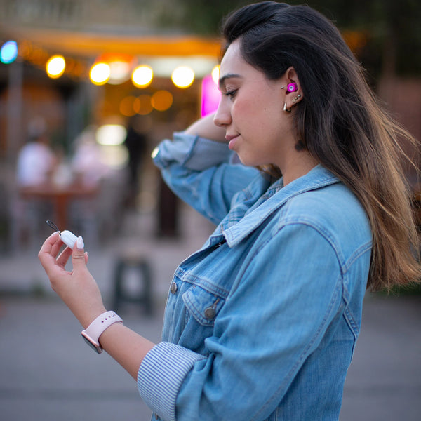 Mujer usando los tapones para los oídos reutilizables Mood Earplugs Chill Pink y sosteniendo su funda de transporte