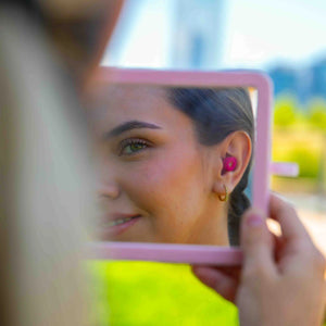 Reflejo de una mujer usando los tapones para los oídos reutilizables Mood Earplugs Chill Pink, símbolo de bienestar y calma