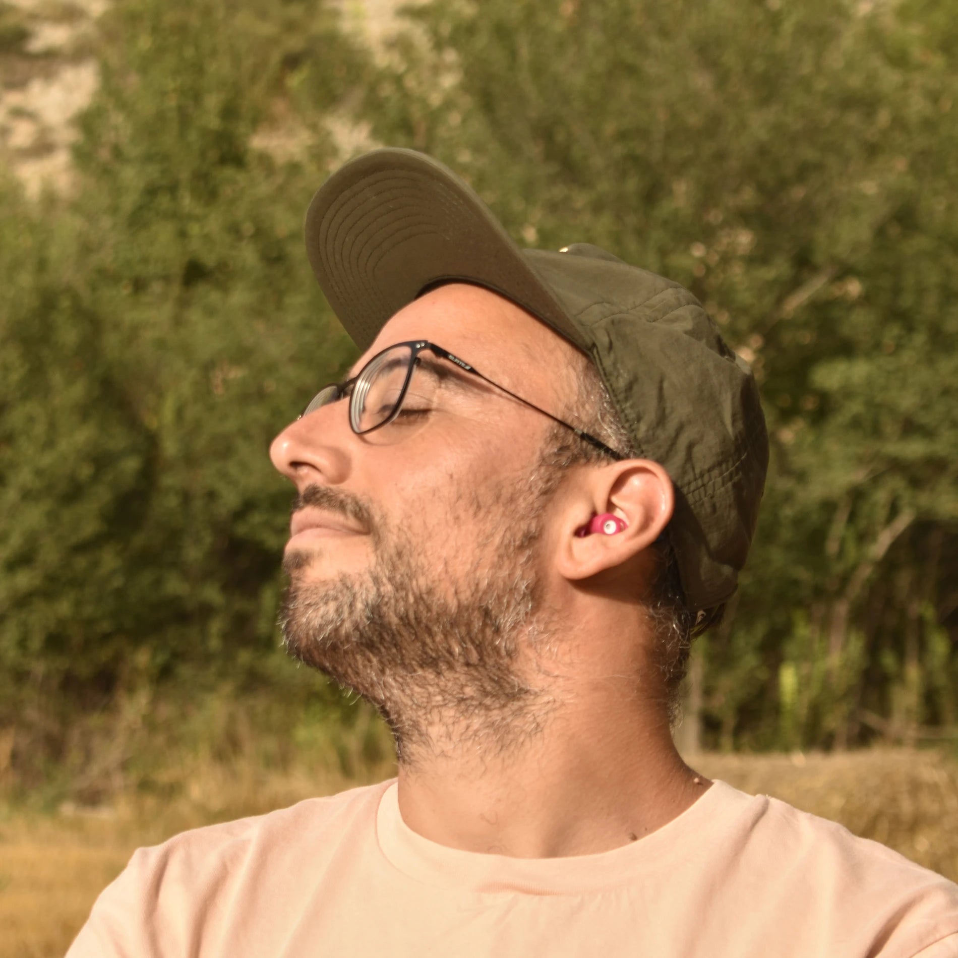 Hombre disfrutando del silencio con los tapones para los oídos reutilizables Mood Earplugs Chill Pink en un entorno natural