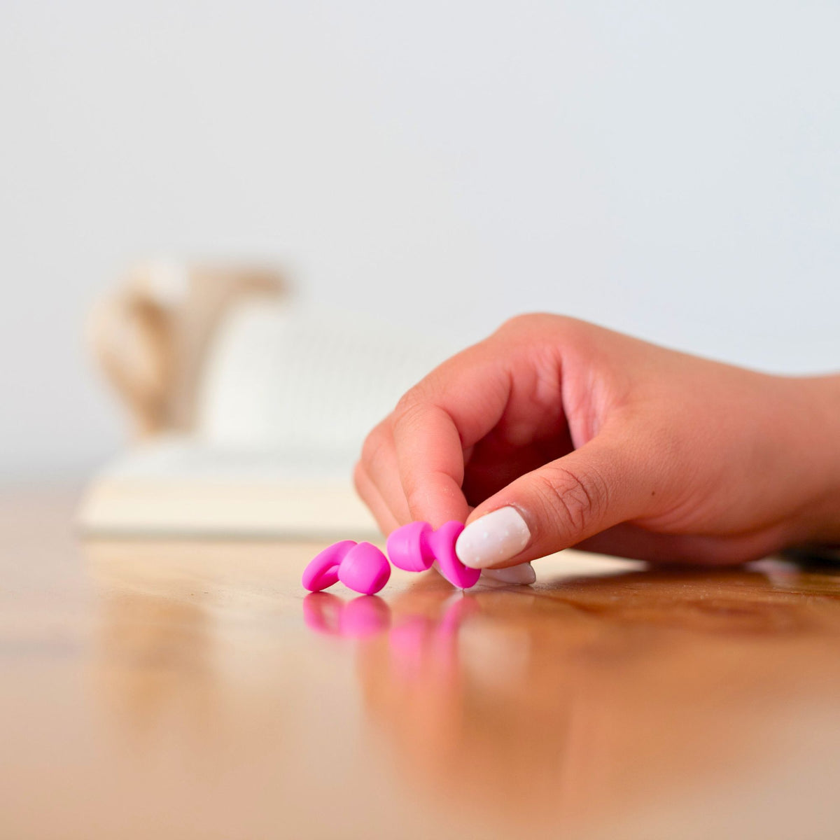 Mano sosteniendo los tapones para los oídos reutilizables Mood Earplugs Focus Pink sobre una mesa, ideales para concentración y silencio