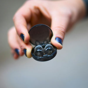 Mano sosteniendo la funda con los tapones auditivos Mood Earplugs Pro Onyx (gris), reutilizables y con máxima protección sonora de 38 dB